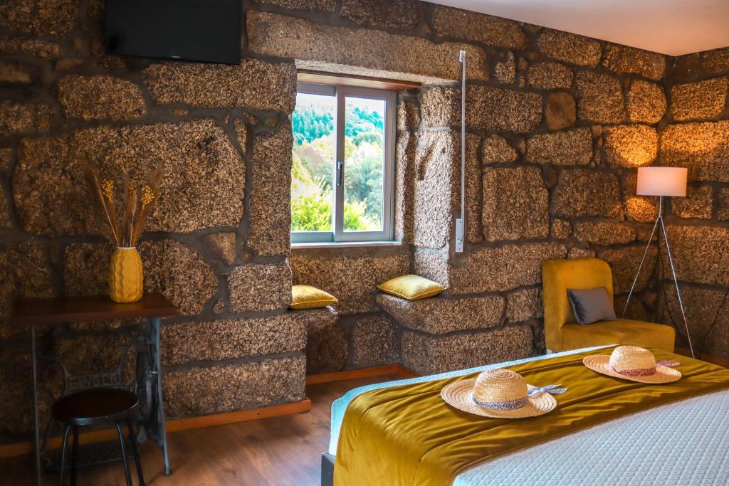 吉马良斯Quinta de Requeixo的一间卧室设有石墙、一张床和一个窗口