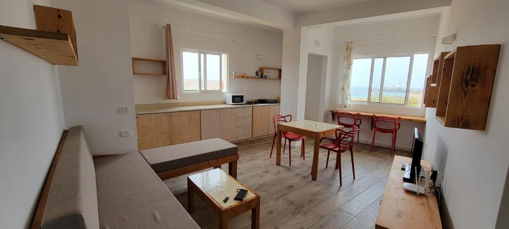 PalmeiraBaia Palmeira Residence的客厅设有厨房、桌子和椅子