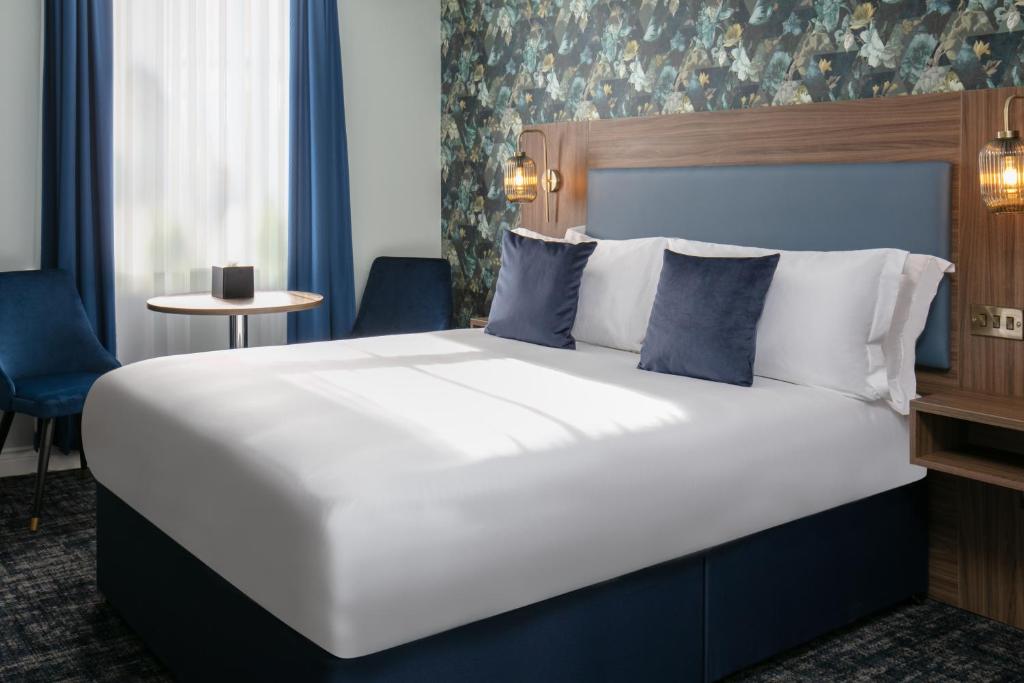 布莱克本Best Western Hotel 99的卧室配有带蓝色枕头的大型白色床