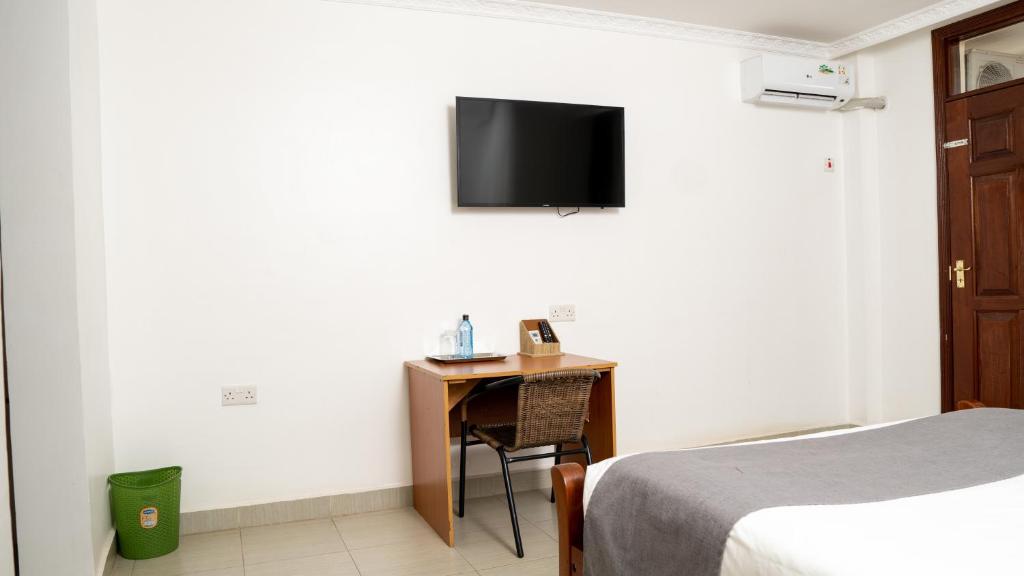 基苏木Whirlspring Hotel的客房设有一张床和一张桌子,墙上配有电视