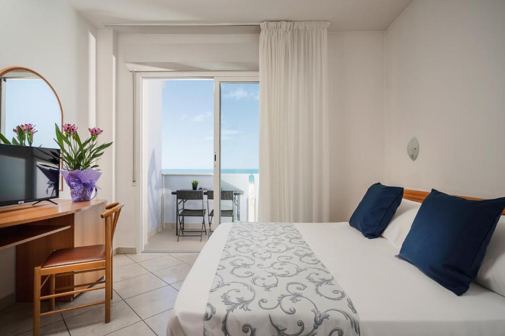 里米尼皮卡迪利酒店的一间卧室配有一张床、一张书桌和一个窗户。