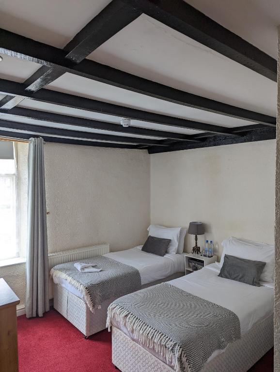 利德尼George Inn st briavels的一间卧室设有两张床和横梁天花板。