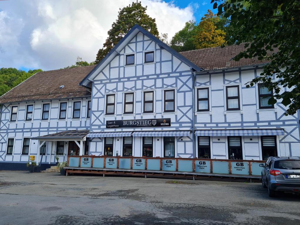 StiegeGasthaus "Burgstieg"的一座蓝色和白色的建筑,前面有停车位