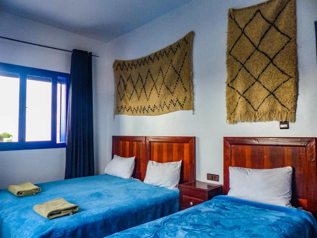 西迪考乌奇Dar Iziki的配有蓝色床单的客房内的两张床