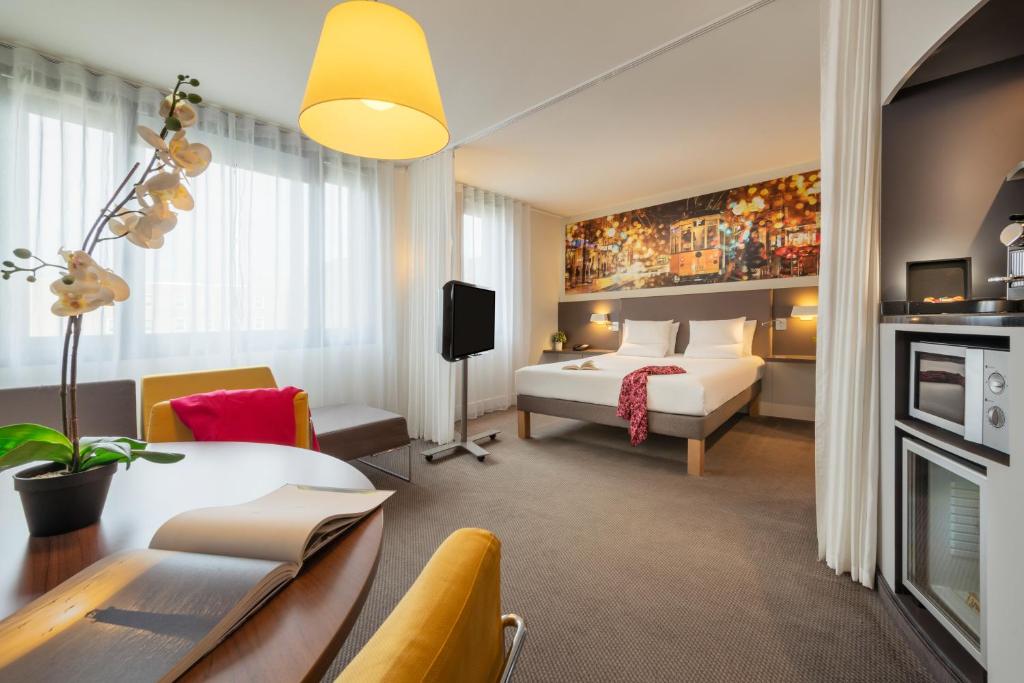 鲁瓦西昂法兰西诺富特套房酒店 - 巴黎戴高乐机场维勒班的配有一张床和一张书桌的酒店客房
