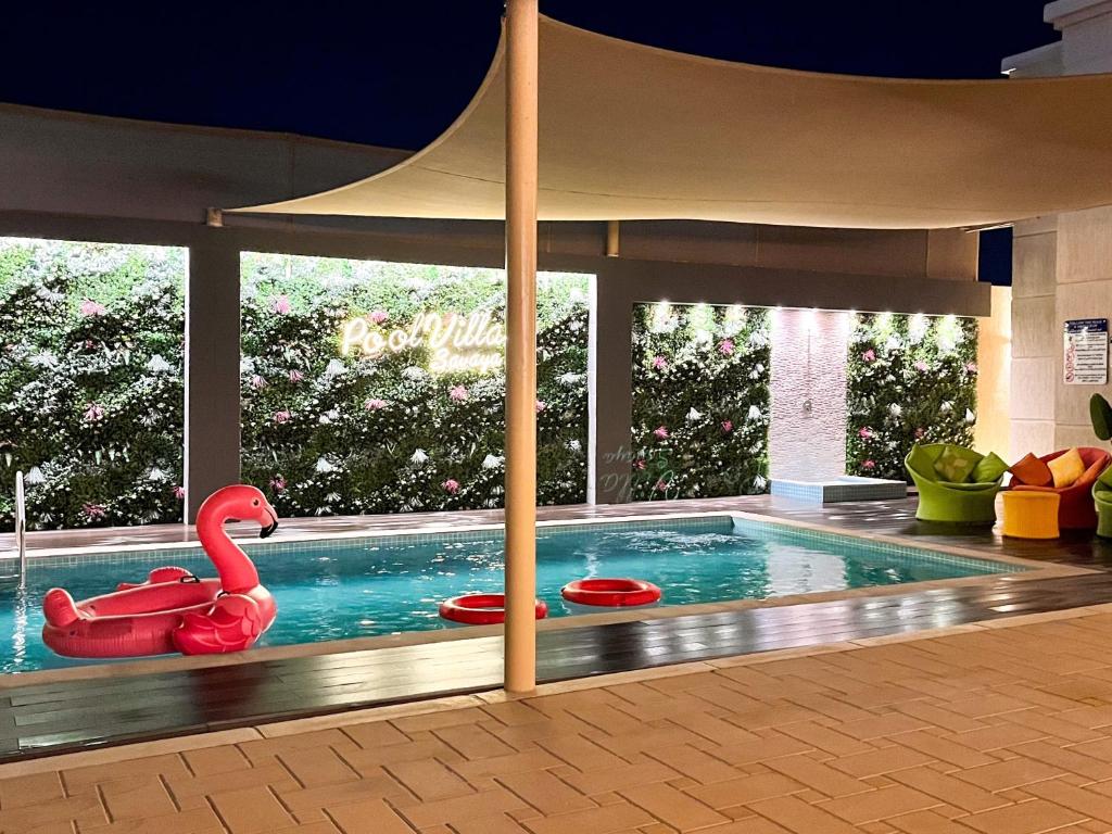 拉斯阿尔卡麦Pool Villa Saraya的一座建筑里的一个游泳池,上面有红色的天鹅