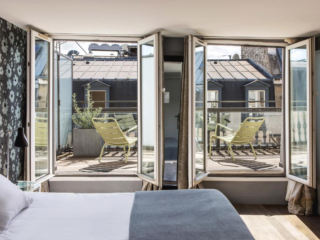 巴黎New Hotel Roblin的一间卧室配有一张床,阳台配有椅子