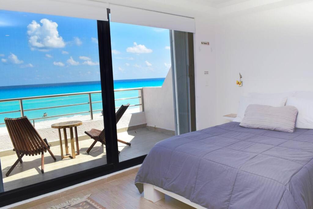 坎昆Ocean front Villa Marlin, best location in hotel zone #109的一间卧室设有一张床和一个海景阳台