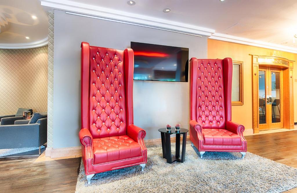 海德堡海德堡莱昂纳多酒店的两个红色椅子坐在房间里