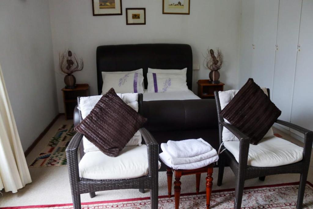 约翰内斯堡Bougainvillea at Boskruin的一间卧室配有一张床和两把椅子