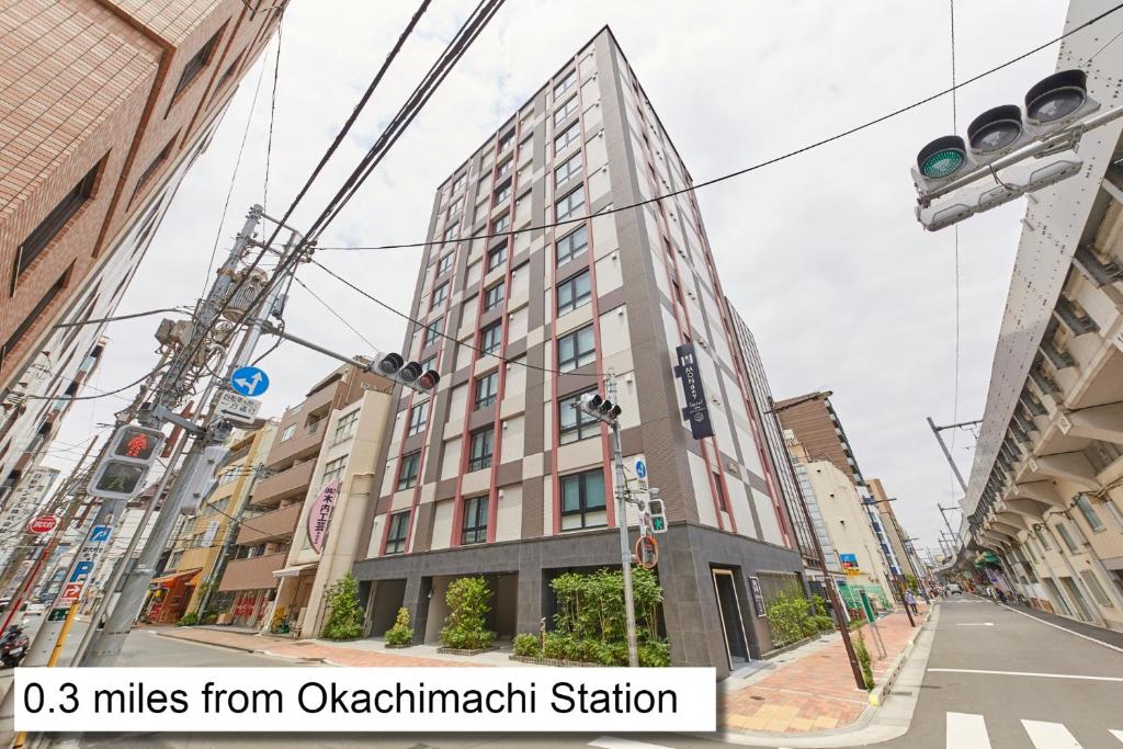 东京MONday Apart Premium UENO OKACHIMACHI的城市街道上一座高大的建筑,有交通灯