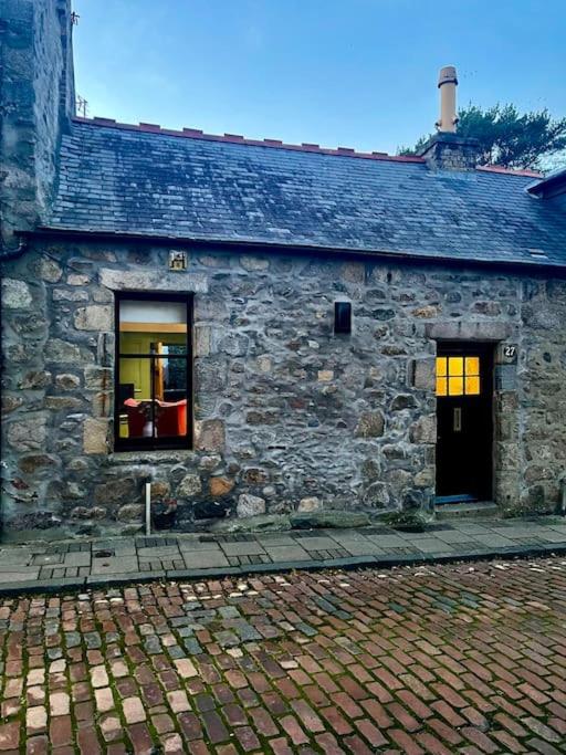 阿伯丁Historic Cottage in the Heart of Old Aberdeen.的一座石头建筑,设有两扇窗户和一扇门
