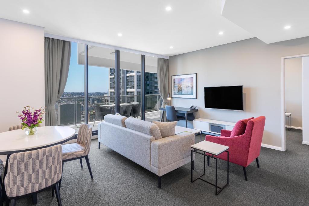 悉尼Meriton Suites Kent Street, Sydney的客厅配有沙发、椅子和电视