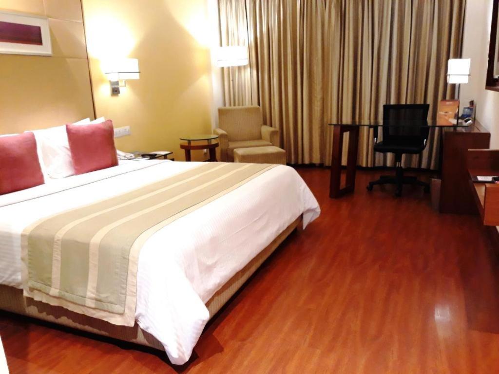 古尔冈古尔冈丽柏酒店的酒店客房设有一张大床和一张书桌。