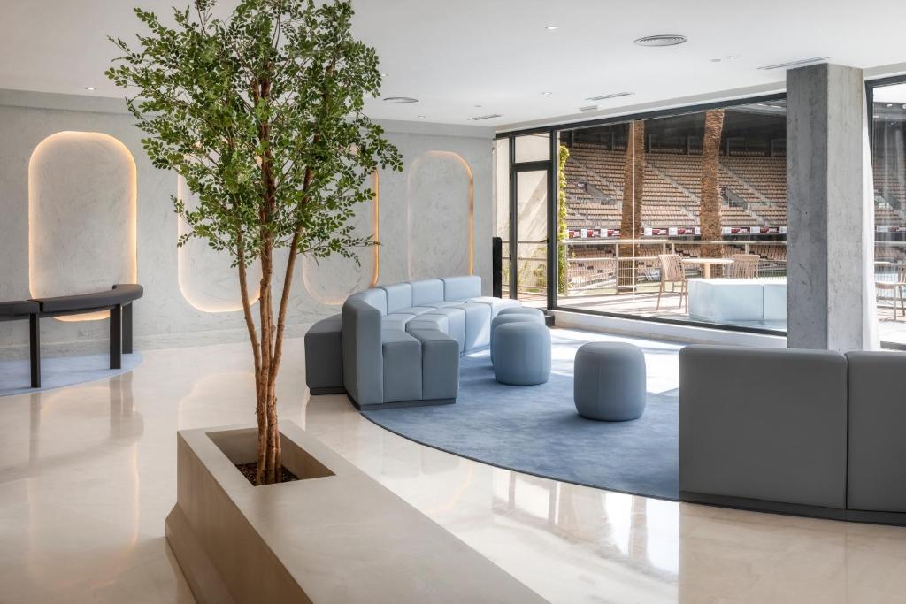 赫雷斯-德拉弗龙特拉B&B HOTEL Jerez的大堂配有树、椅子和桌子