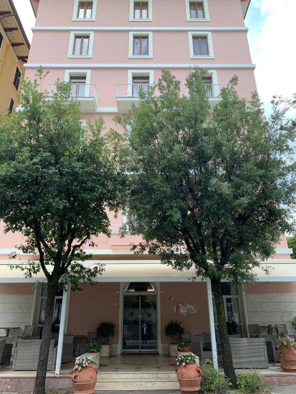蒙特卡蒂尼泰尔梅比昂迪酒店的粉色建筑前两棵树