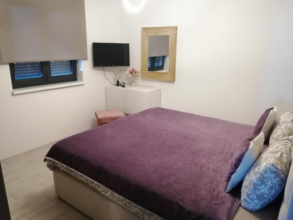 奈维斯Golden Sunset的一间卧室配有一张紫色的床和一台电视机