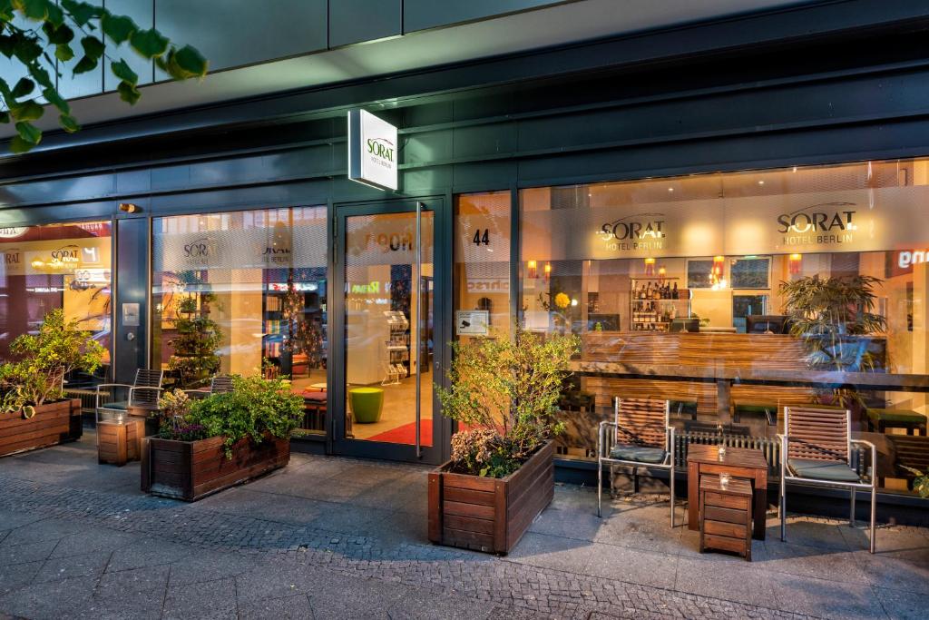柏林SORAT Hotel Berlin的商店前方设有桌椅和植物