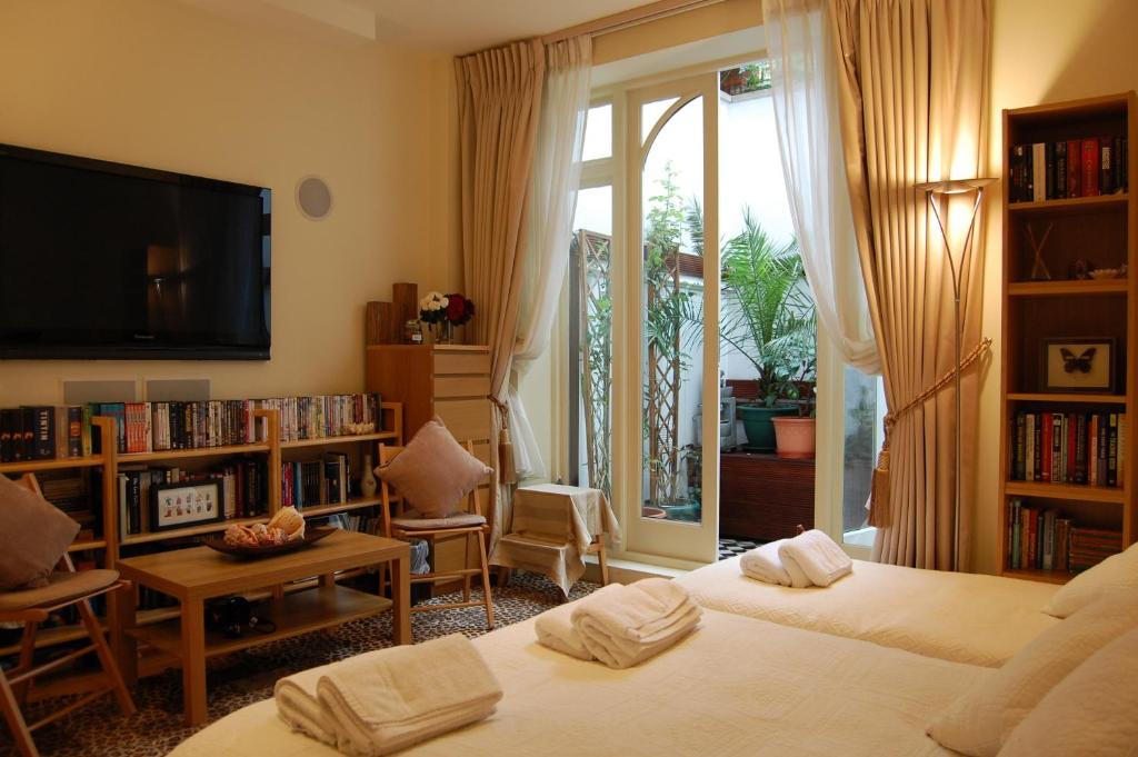 伦敦Georgiana's Guesthouse的一间卧室设有两张床、一台电视和书架