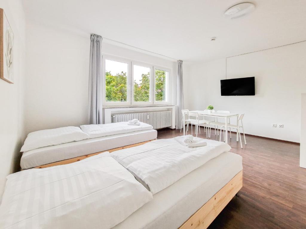 杜伊斯堡RAJ Living - 1 or 3 Room Apartments - 30 Min Messe DUS的配有两张床铺、一张桌子和一台电视机的客房