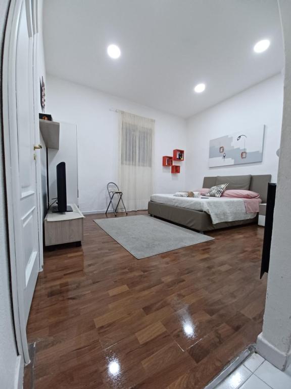 那不勒斯Vima's home的卧室拥有白色的墙壁和一张床,铺有木地板