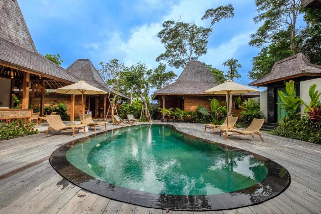 坎古Kaju Apartment by Hombali的度假村的游泳池,配有椅子和遮阳伞