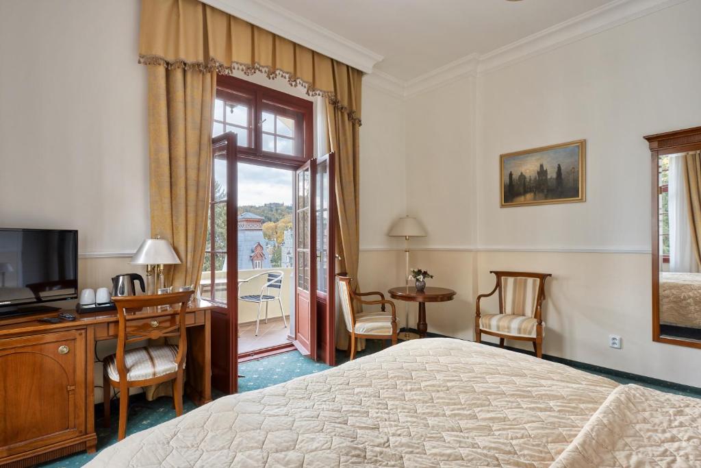卡罗维发利Spa Hotel Villa Ritter的一间卧室配有一张床、一台电视和一个阳台