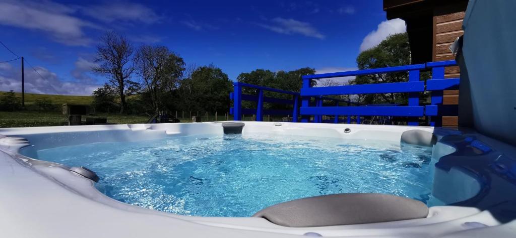 新卡姆诺克Glen Roe - 3 Bed Lodge on Friendly Farm Stay with Private Hot Tub的设有一个蓝色水的按摩浴缸