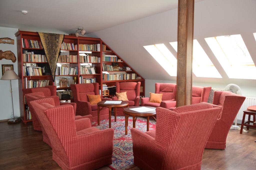 HerendHolló és Bárány Vendégház的图书馆配有红色的椅子和桌子以及书架