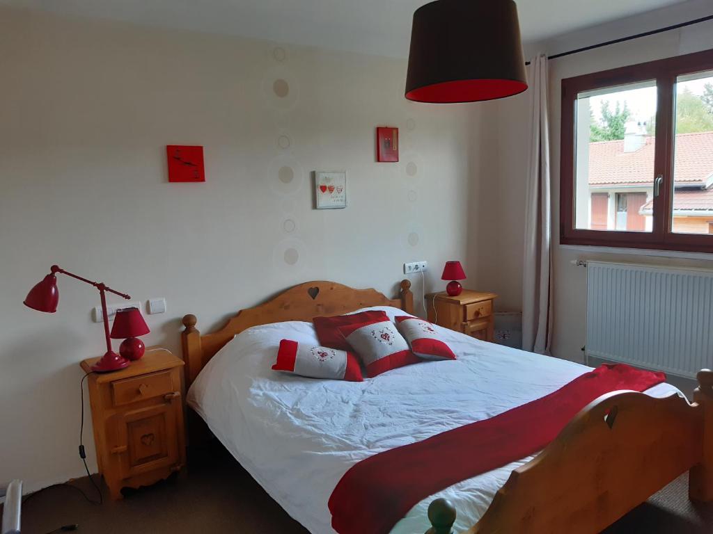 莱鲁斯Au doux passage的一间卧室配有一张带红色枕头的床和一扇窗户