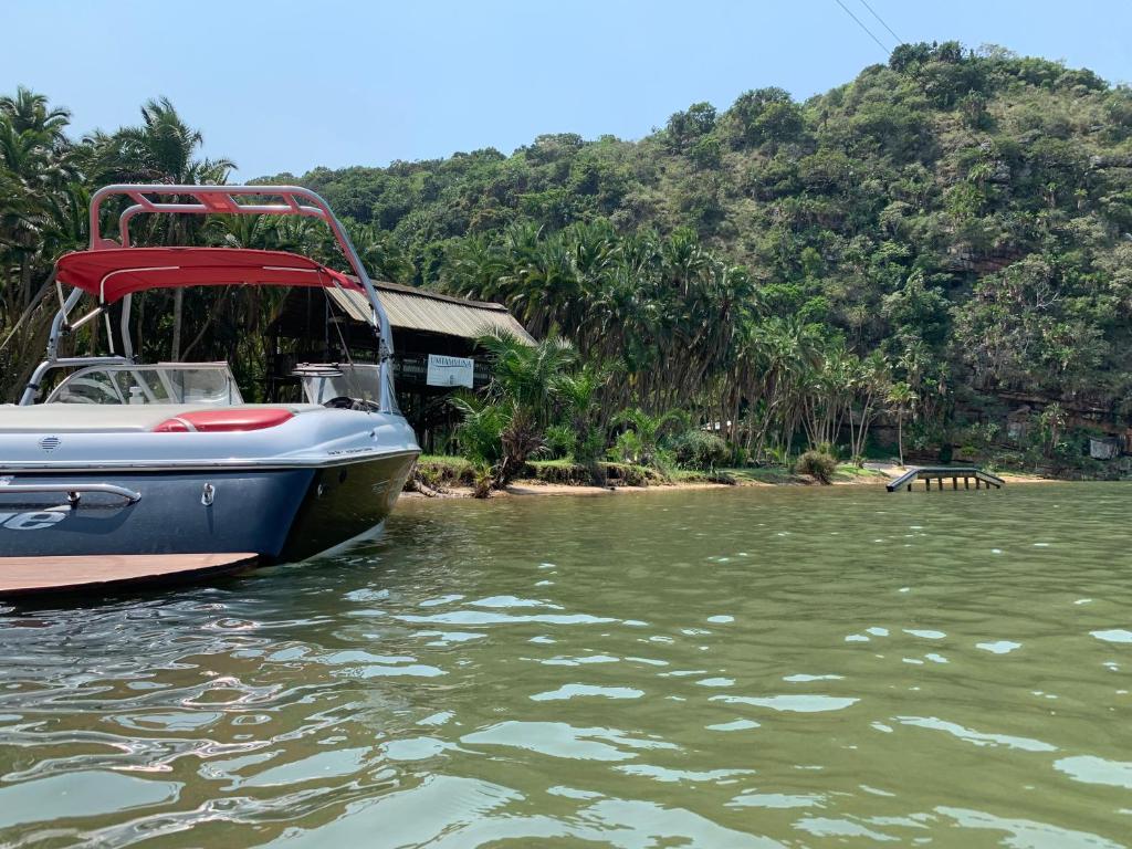 爱德华港Umtamvuna River Lodge的坐在房子旁边的水面上的船