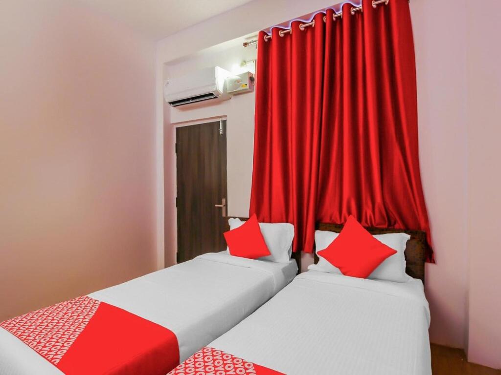 海得拉巴HZ INN的配有红色窗帘的客房内的两张床