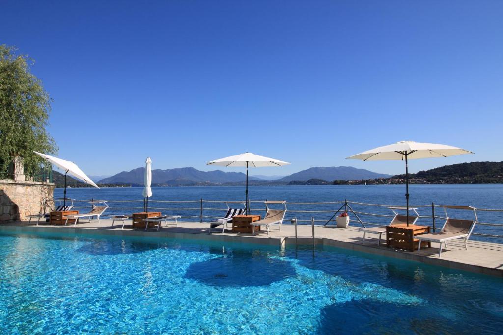 梅纳Resort Antico Verbano的水边带椅子和遮阳伞的游泳池