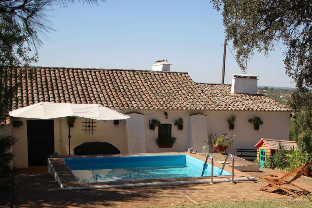 埃武拉Casa das Moles的一座带游泳池和遮阳伞的房子