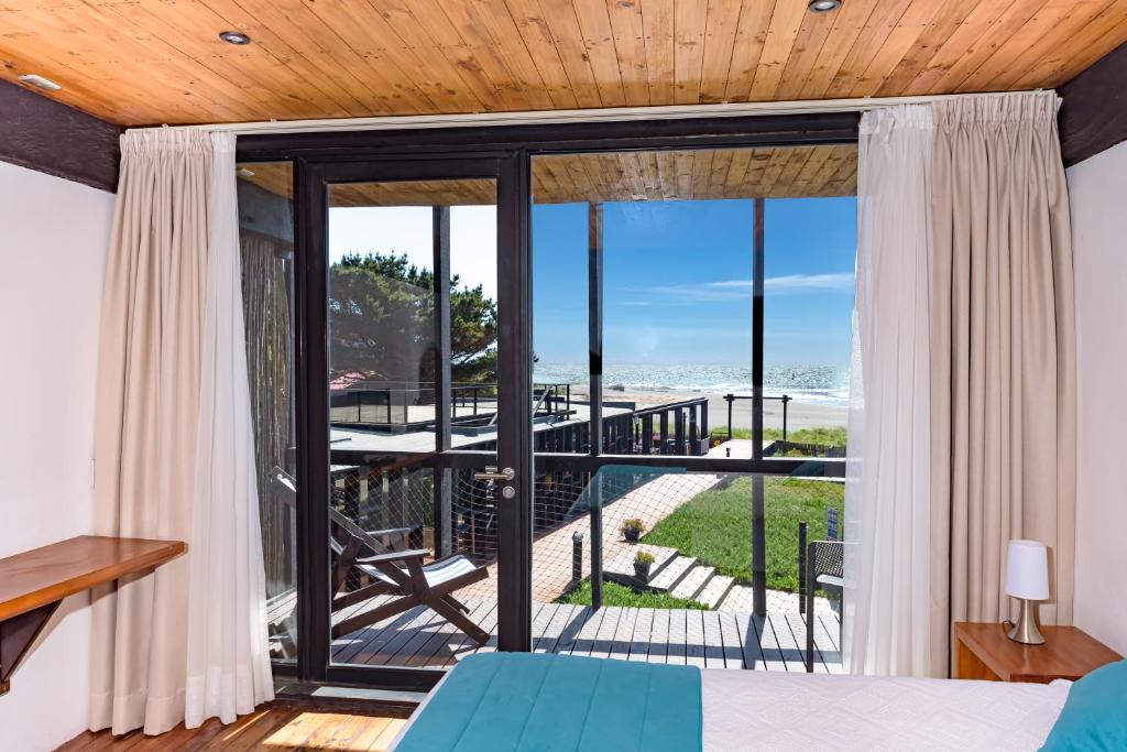 库雷尼佩Hotel Punta Sirena的卧室设有玻璃门,享有海滩美景