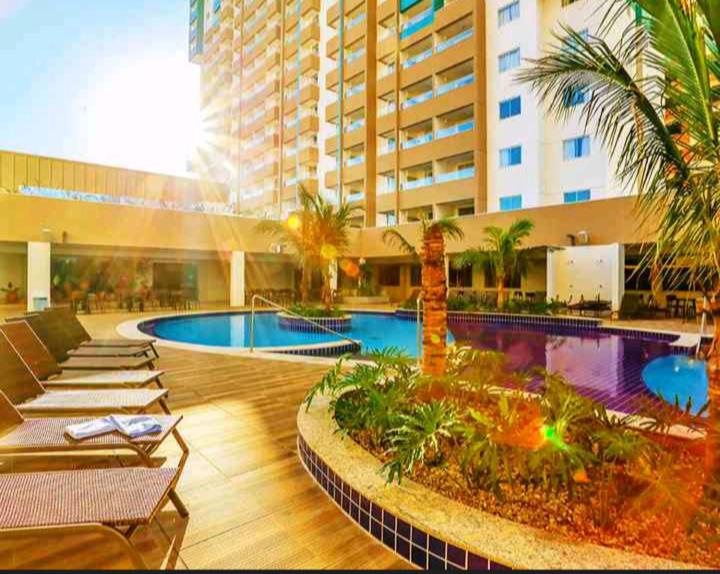 奥林匹亚Olímpia Park Resort-frente Thermas Laranjais-apt 5 p的一座拥有游泳池、棕榈树和建筑的酒店