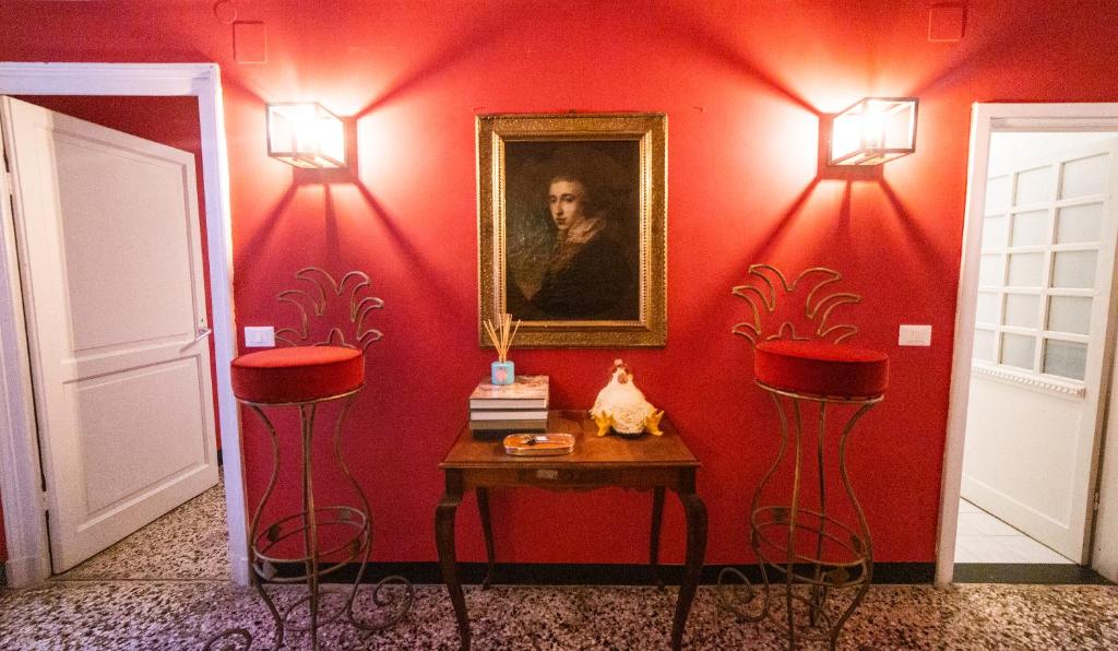 热那亚The Apartment Genova的红色的房间,设有两张凳子、一张桌子和一幅画