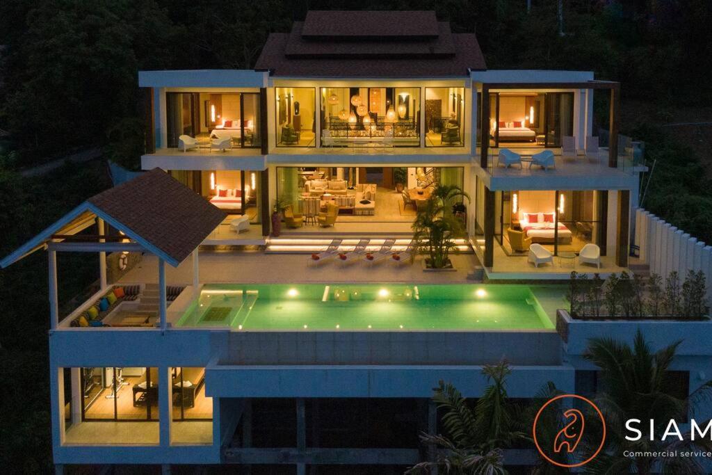 苏梅岛Jungle Beach Villa的一座在晚上设有游泳池的大房子