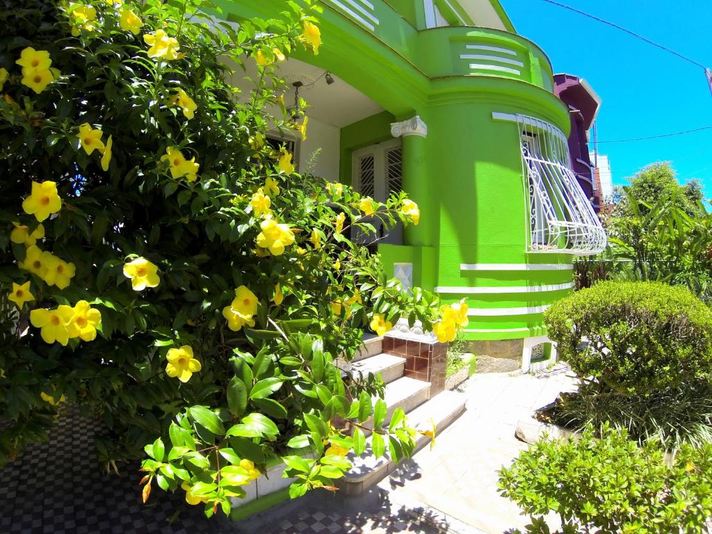 阿雷格里港POA Eco Hostel的前面有黄色花的绿色房子