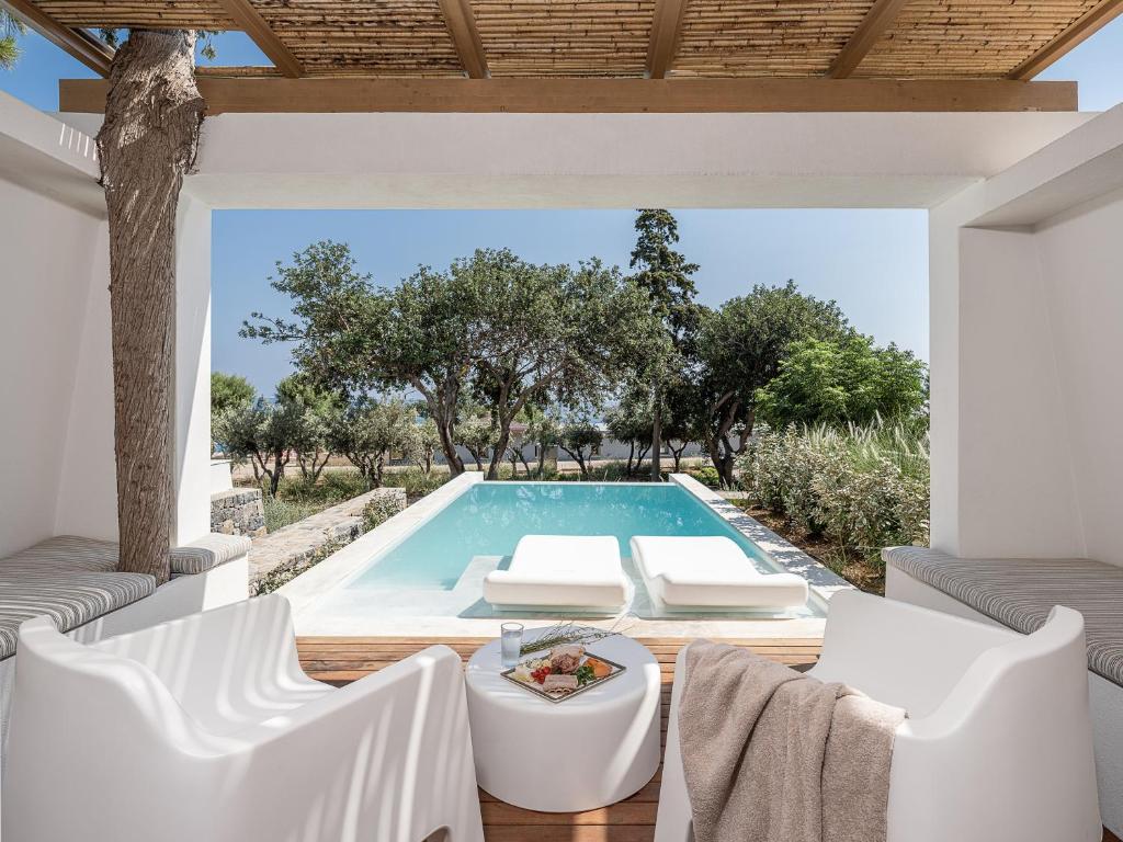 依拉佩特拉卡科斯海湾简易别墅酒店的一个带白色椅子和桌子的游泳池