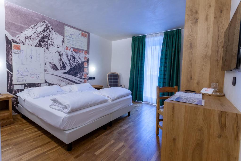 库马约尔贝桃德酒店的卧室配有白色的床和带书桌的书桌