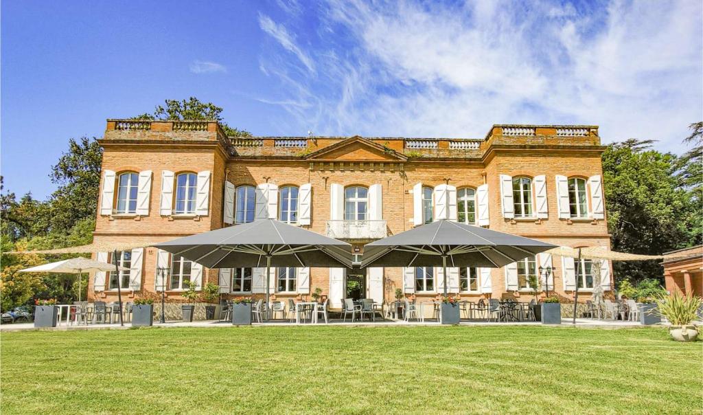 拉蒙维尔圣阿尼Domaine de Montjoie - Toulouse - BW Premier Collection的一座大型砖砌建筑,前面设有桌子和遮阳伞