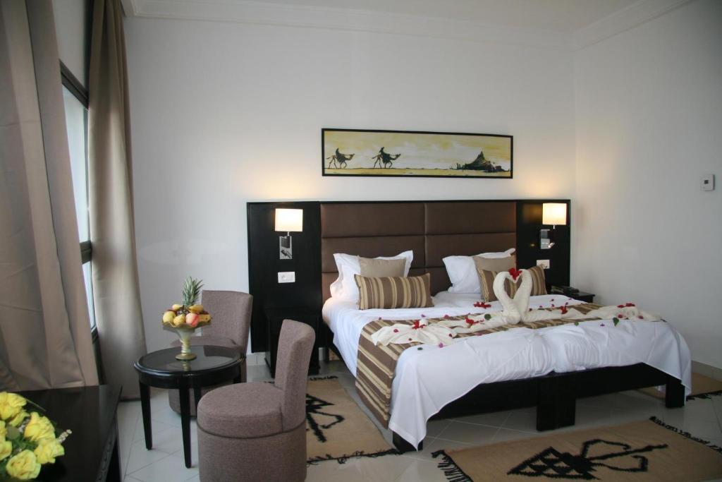 DjerbaHOTEL OLYMPIC DJERBA的酒店客房,配有两张床和椅子