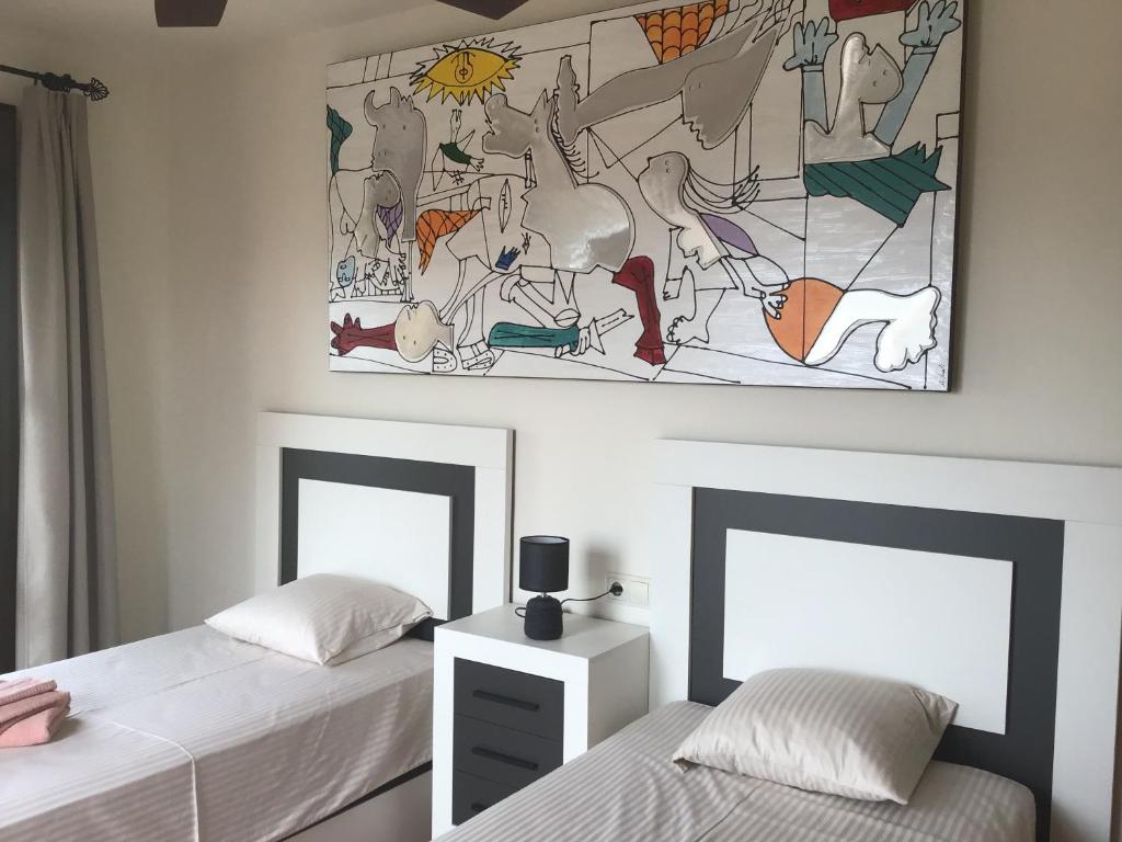 维拉Rincón de Vera - Ático的一间卧室设有两张床,墙上挂着一幅画