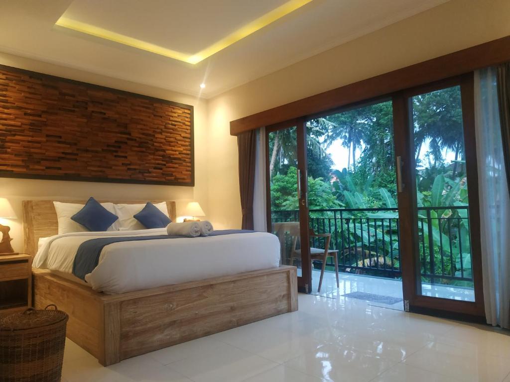 乌布Cahaya Guest House的一间带大床的卧室和一个阳台