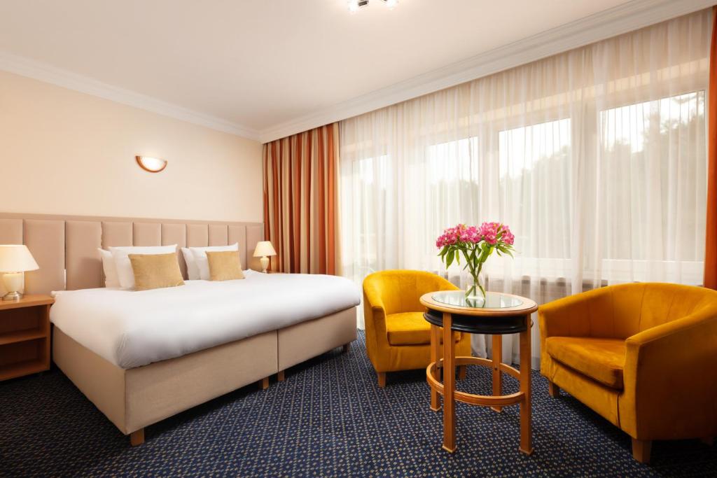 纳达金Perła Leśna Nadarzyn的酒店客房带一张床、一张桌子和椅子