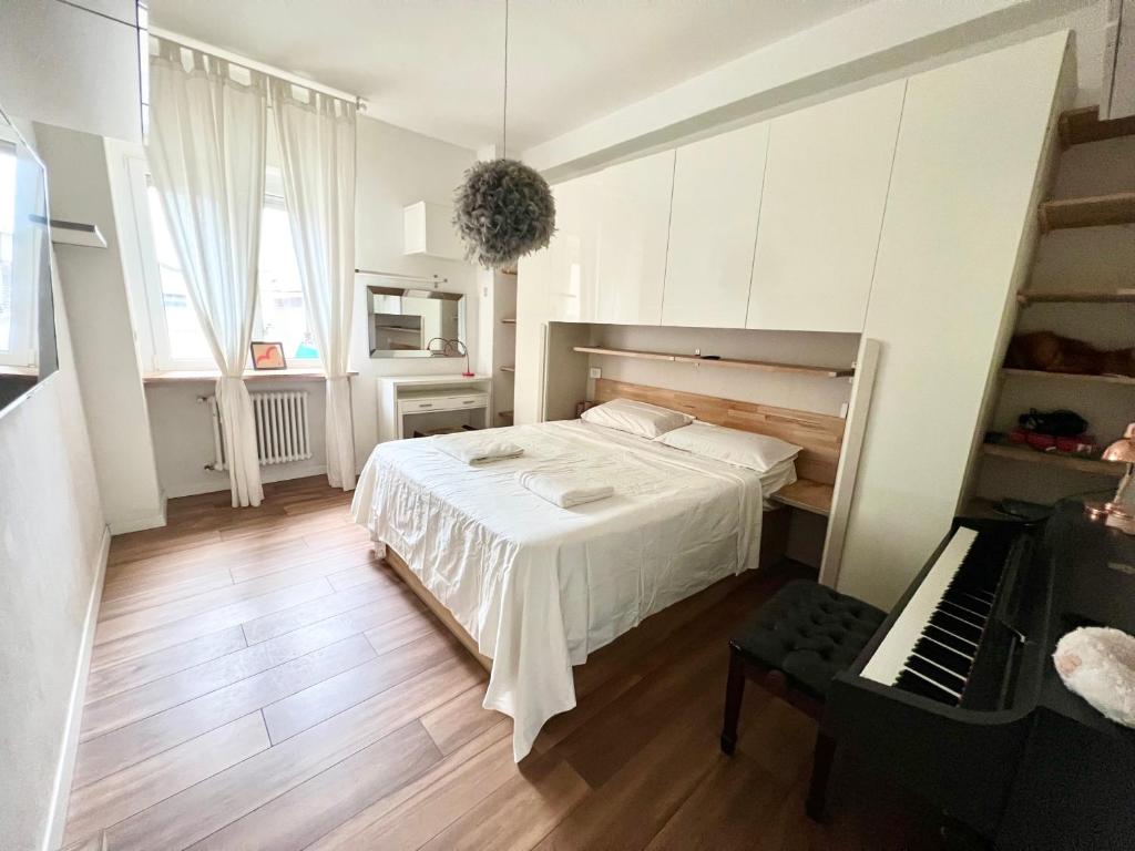 塞格拉泰white home near Linate的卧室配有白色的床和钢琴