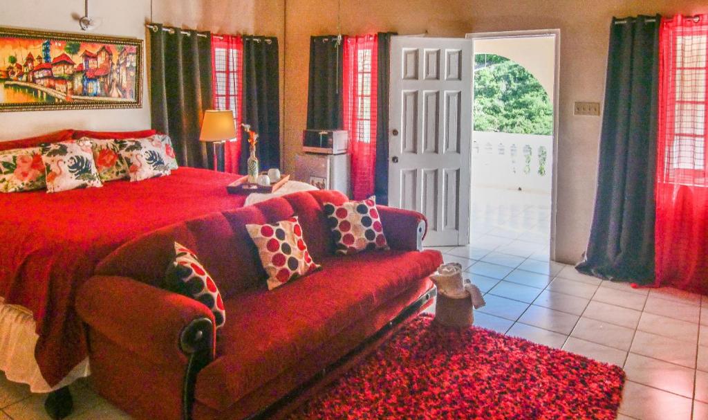 金斯敦876 JA Oasis & Homestay - by Kingston Airport的一间卧室配有红色的床和一张沙发