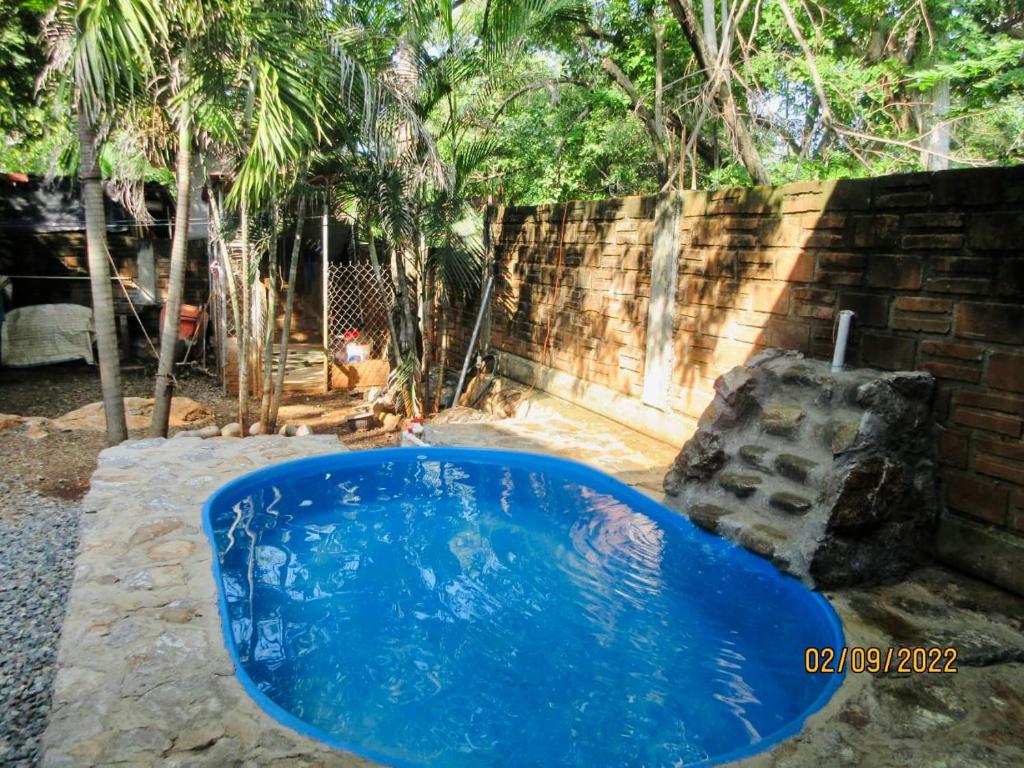 特隆戈内斯Casita Monarca的一座带砖墙的庭院中的蓝色游泳池