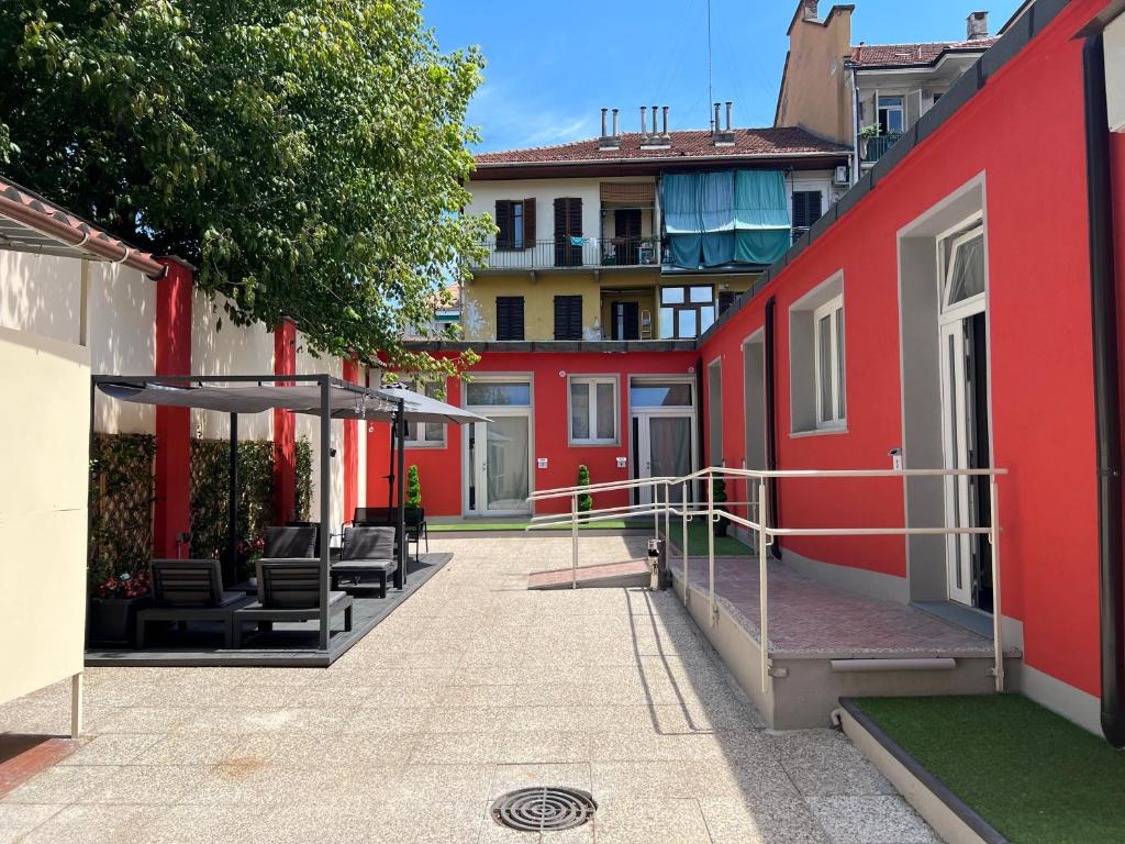 都灵Hostel Turin Metro Young的庭院里一座红色的建筑,配有椅子和遮阳伞